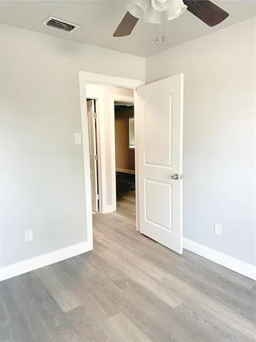 an empty room with wooden floor and a ceiling fan