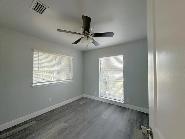 a view of empty room with wooden floor and fan