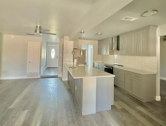 a large white kitchen with wooden floor and stainless steel appliances