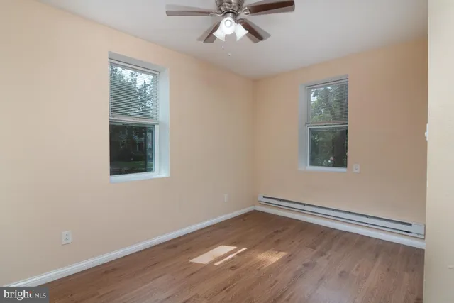 a view of empty room with wooden floor and fan