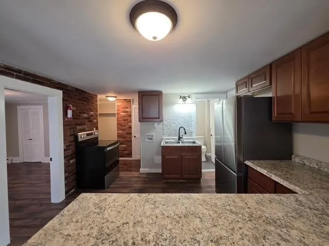 a kitchen with kitchen island granite countertop a refrigerator stove top oven and sink