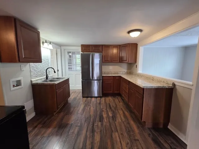 a kitchen with stainless steel appliances granite countertop a refrigerator a sink and wooden cabinets