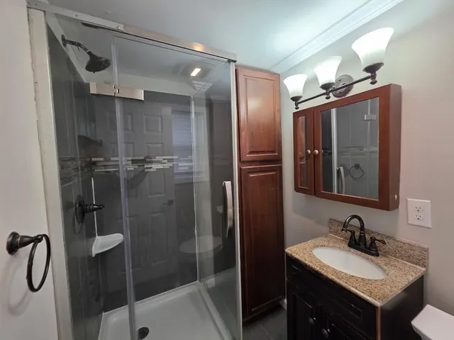a bathroom with a sink vanity granite tub shower and mirror