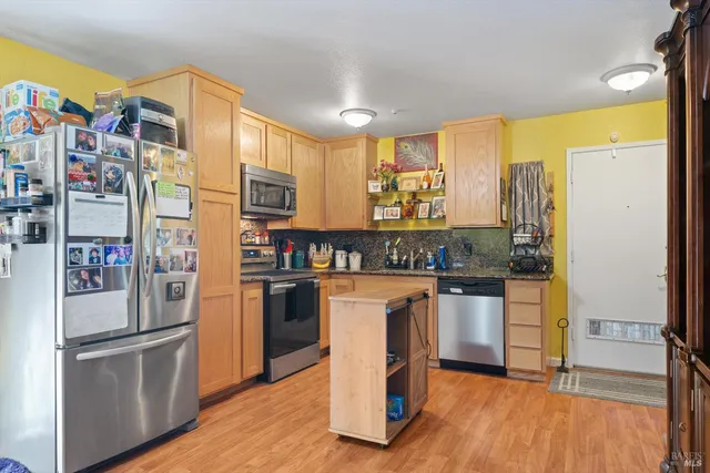 a kitchen with stainless steel appliances granite countertop a refrigerator a stove and a sink