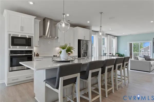a kitchen with stainless steel appliances kitchen island granite countertop a dining table chairs and white cabinets