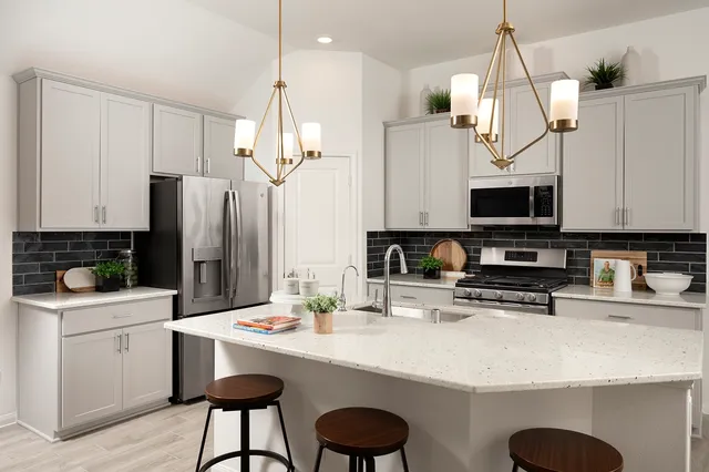 a kitchen with stainless steel appliances a stove a sink a microwave a refrigerator and white cabinets