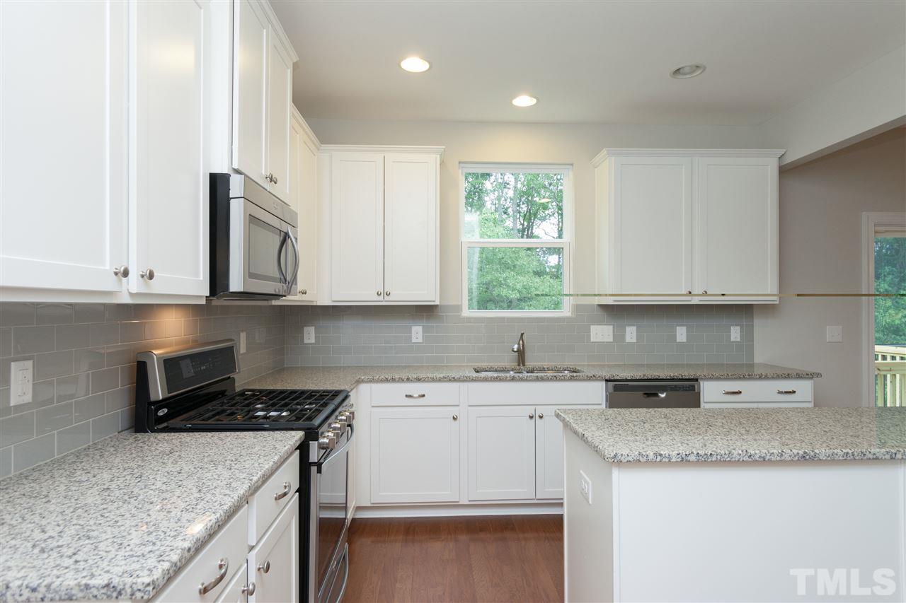 113 Spring Pine Lane Holly Springs, NC 27540 - Photo 5 of 25 a kitchen with granite countertop cabinets sink and stove