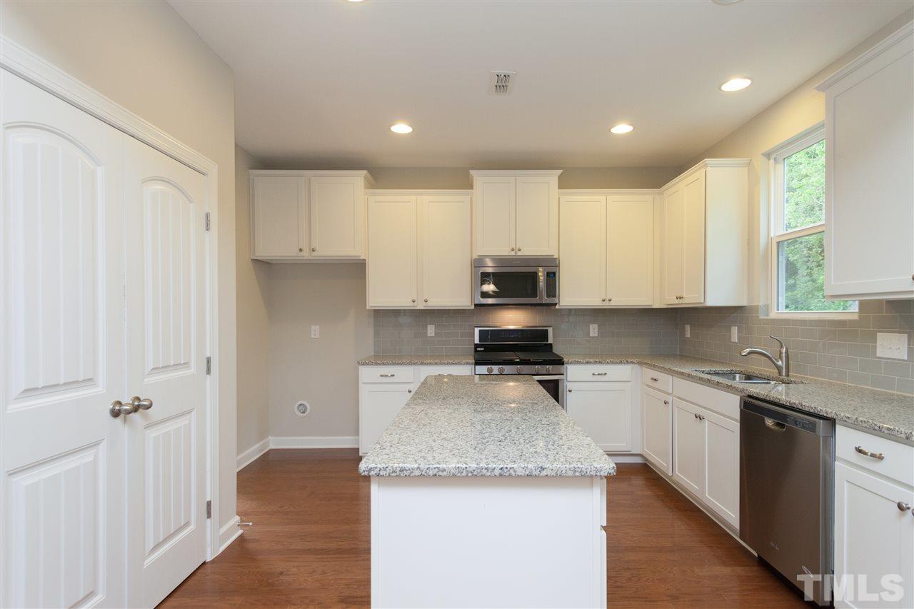 113 Spring Pine Lane Holly Springs, NC 27540 - Photo 8 of 25 a kitchen with stainless steel appliances granite countertop a sink a stove and a refrigerator