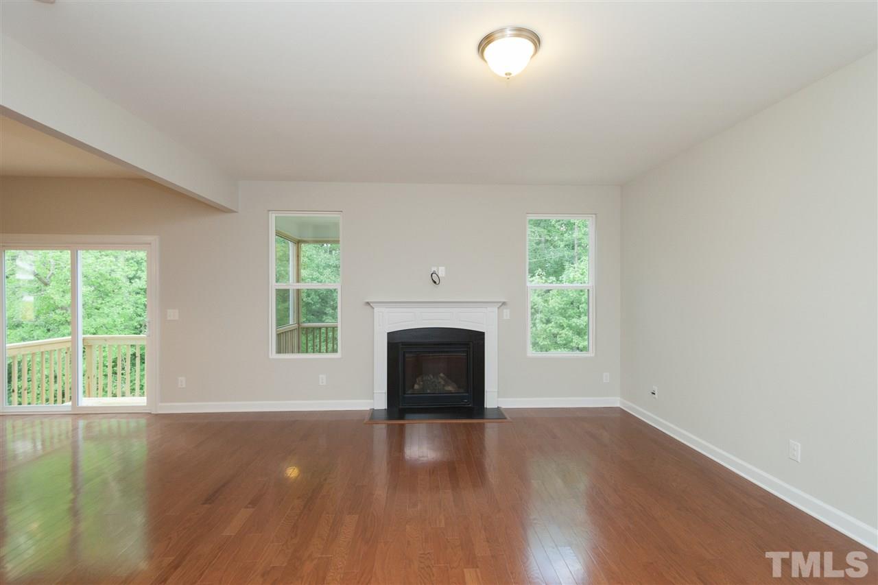 113 Spring Pine Lane Holly Springs, NC 27540 - Photo 9 of 25 an empty room with wooden floor fireplace and windows