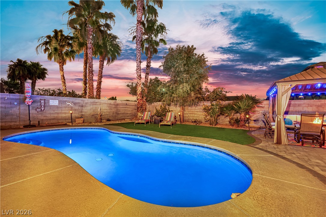 1724 Millstream Way Henderson, NV 89074 - Photo 55 of 60 A vibrant oasis featuring a sparkling in-ground pool and a chic covered patio under a captivating sky.