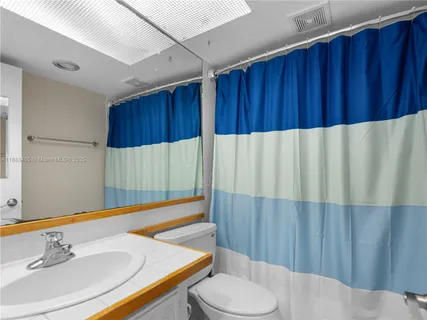 a bathroom with a sink a toilet and shower curtain