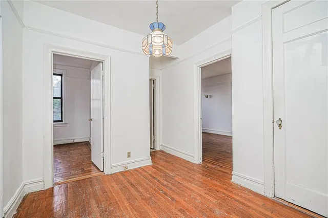 a view of a hallway with wooden floor and a chandelier