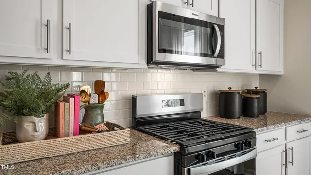 a kitchen with granite countertop a refrigerator a stove a sink a dining table and chairs