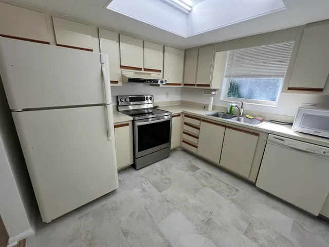 a kitchen with stainless steel appliances granite countertop a refrigerator a stove a sink and a microwave