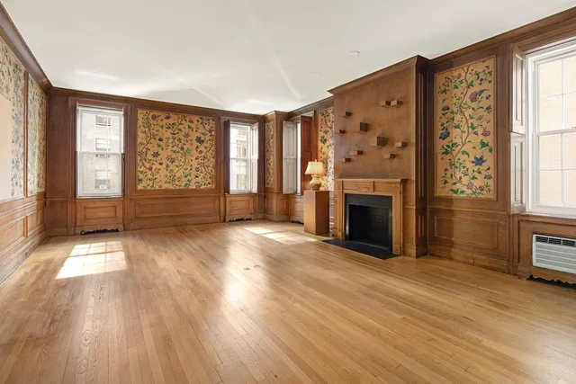 an empty room with windows fireplace and wooden floor