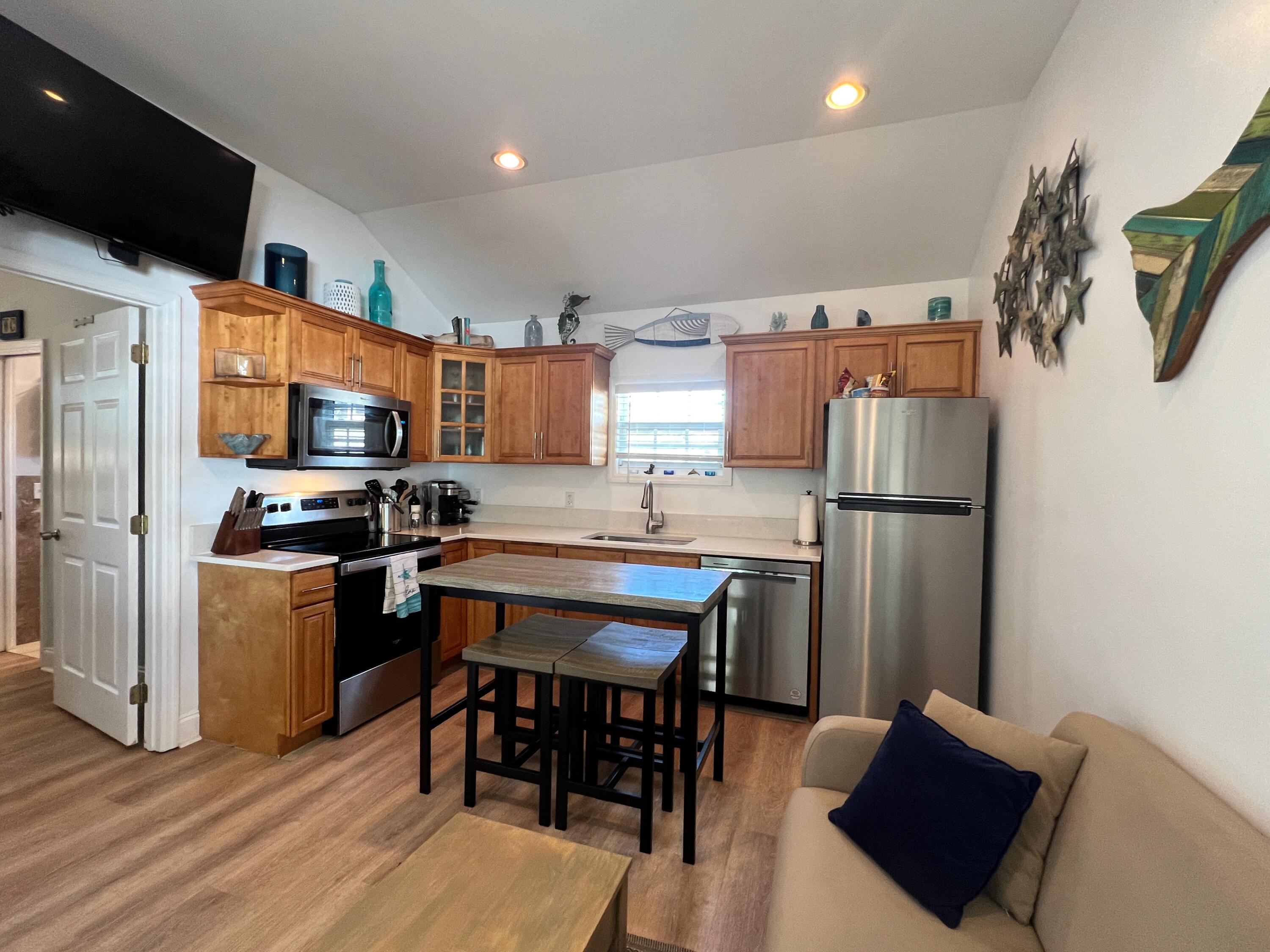 904 Terry Lane, Unit 4 Key West, FL 33040 - Photo 3 of 14 a kitchen with stainless steel appliances granite countertop a refrigerator a stove a sink dishwasher a dining table and chairs with wooden floor