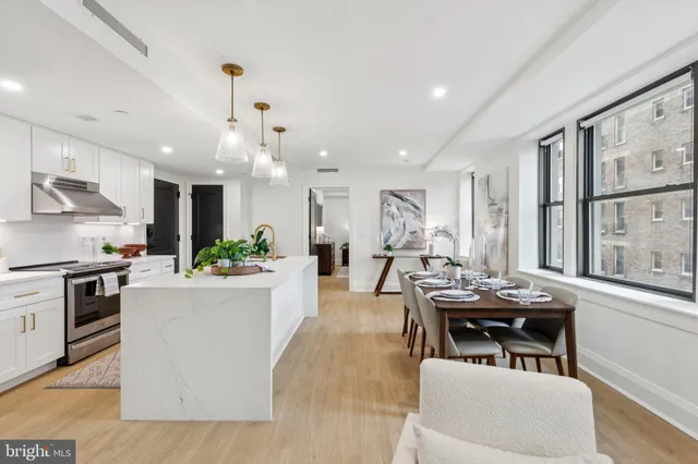 a kitchen with stainless steel appliances kitchen island granite countertop a table chairs stove and white cabinets