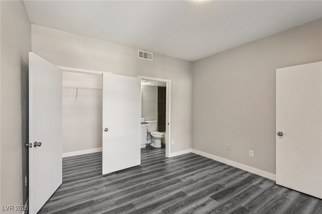 7255 West Sunset Road, Unit 1087 Las Vegas, NV 89113 - Photo 15 of 43 Unfurnished bedroom featuring dark wood finished floors, a spacious closet, and ensuite bathroom