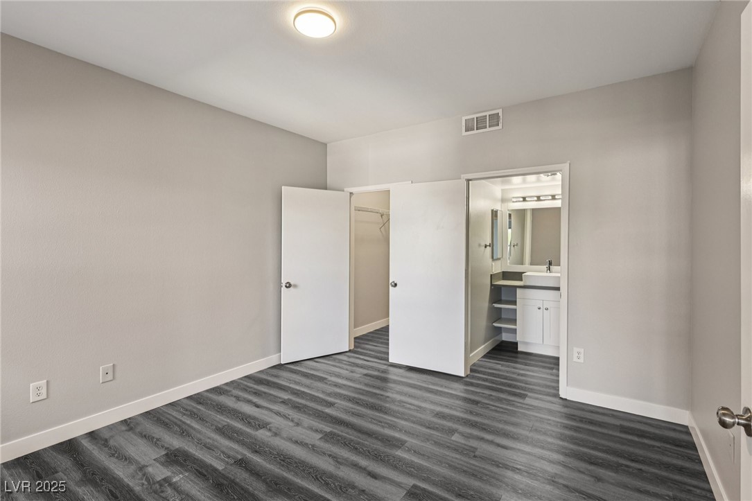 7255 West Sunset Road, Unit 1087 Las Vegas, NV 89113 - Photo 16 of 43 Unfurnished bedroom with dark wood-style flooring, a walk in closet, and ensuite bathroom