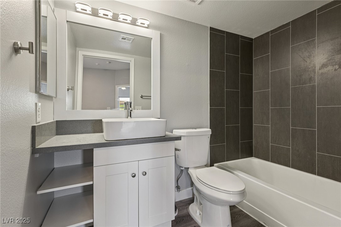 7255 West Sunset Road, Unit 1087 Las Vegas, NV 89113 - Photo 17 of 43 Bathroom with vanity, shower / tub combination, a textured wall, and dark wood-style flooring