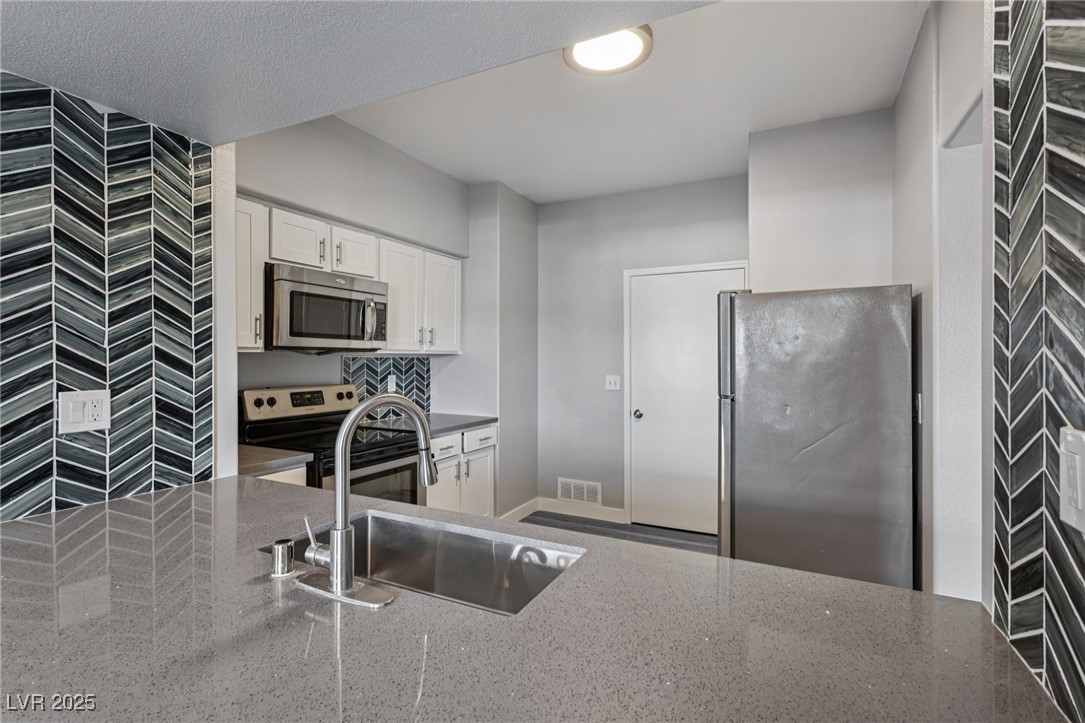 7255 West Sunset Road, Unit 1087 Las Vegas, NV 89113 - Photo 20 of 43 Kitchen with appliances with stainless steel finishes, white cabinetry, and dark stone counters