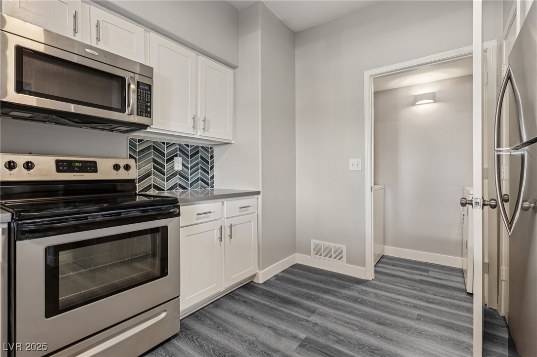 7255 West Sunset Road, Unit 1087 Las Vegas, NV 89113 - Photo 23 of 43 Kitchen with stainless steel appliances, white cabinetry, decorative backsplash, and dark wood-type flooring