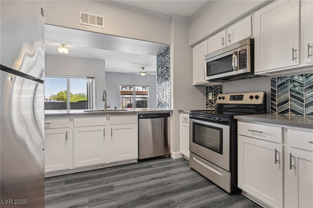 7255 West Sunset Road, Unit 1087 Las Vegas, NV 89113 - Photo 25 of 43 Kitchen featuring stainless steel appliances, white cabinetry, dark wood-style floors, and a ceiling fan