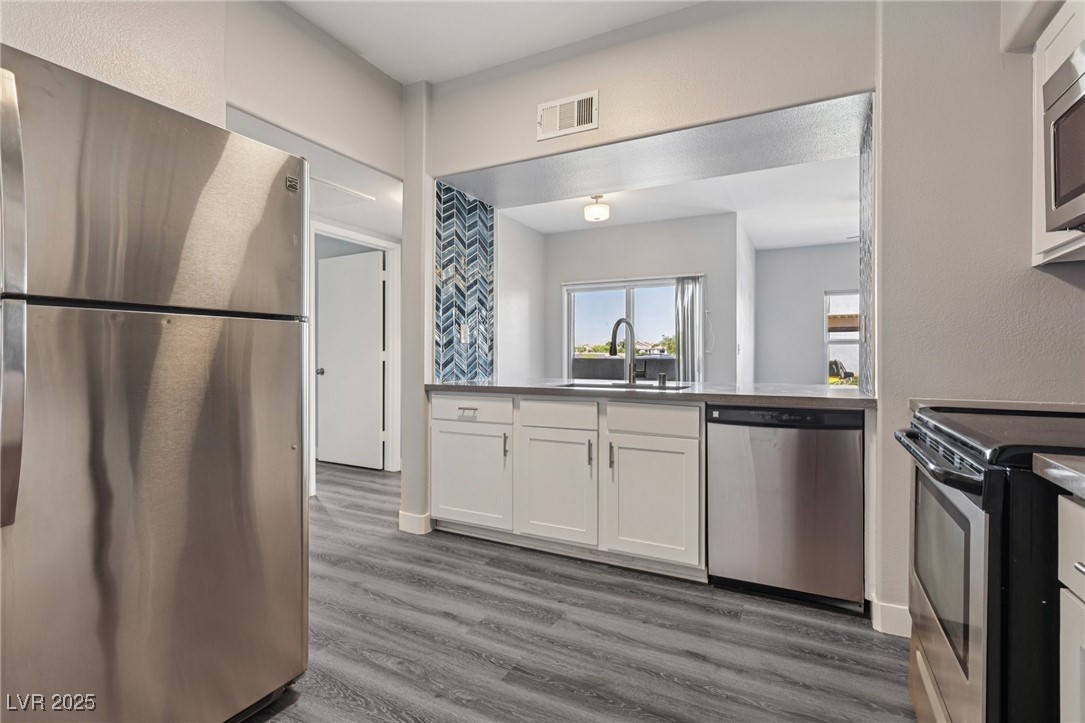 7255 West Sunset Road, Unit 1087 Las Vegas, NV 89113 - Photo 26 of 43 Kitchen with stainless steel appliances, wood finished floors, and white cabinets