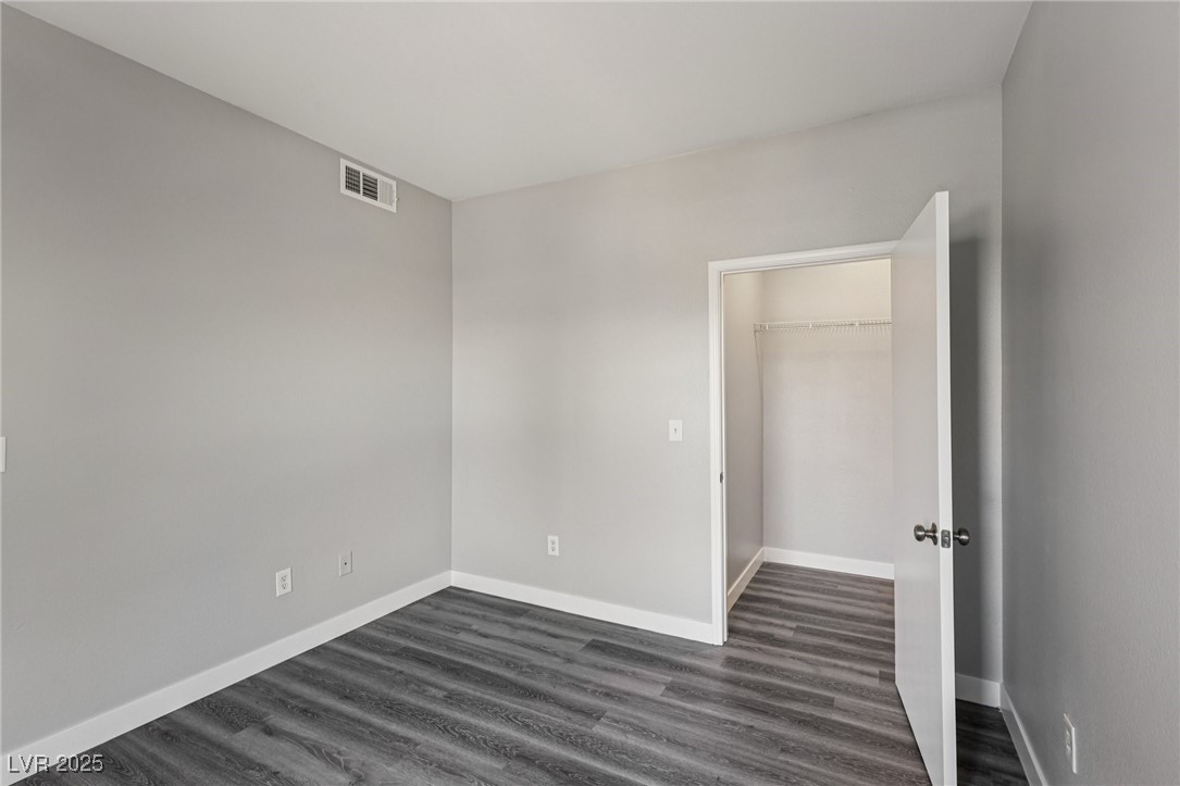 7255 West Sunset Road, Unit 1087 Las Vegas, NV 89113 - Photo 30 of 43 Unfurnished bedroom with dark wood-style flooring and a walk in closet