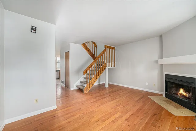 a view of an empty room with wooden floor fireplace and a window