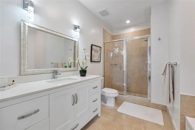 a bathroom with a double vanity sink toilet mirror and shower
