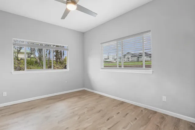 a view of an empty room with a window and wooden floor