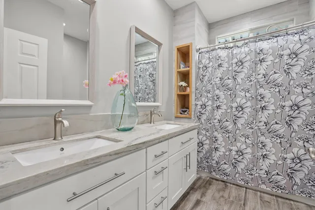 a bathroom with a granite countertop sink a mirror and a shower