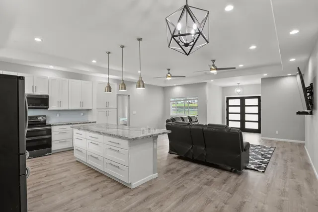 a large living room with stainless steel appliances kitchen island granite countertop a couch and a view of living room