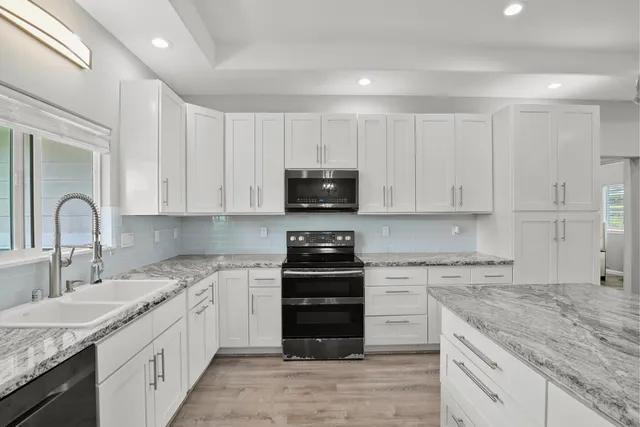 a kitchen with granite countertop white cabinets and appliances