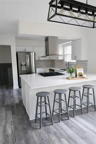 a kitchen with stainless steel appliances a table and chairs in it
