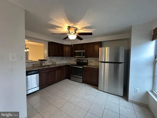 a kitchen with stainless steel appliances granite countertop a refrigerator a sink a stove top oven and a dishwasher
