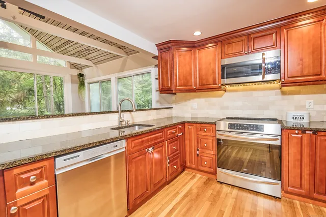 a kitchen with stainless steel appliances granite countertop a sink stove and cabinets