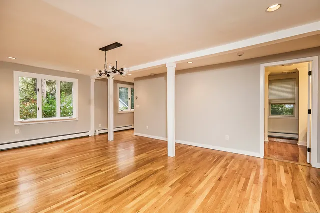 an empty room with wooden floor cabinet and windows