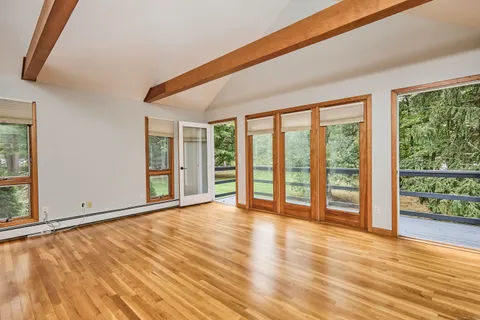 a view of an empty room with wooden floor and a window