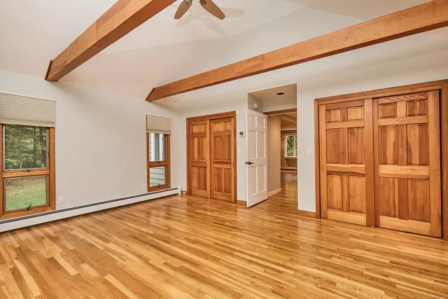a view of an empty room with window and wooden floor