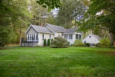 a front view of a house with a garden and trees