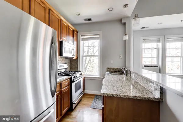 a kitchen with granite countertop stainless steel appliances a sink stove and refrigerator