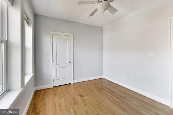 a view of an empty room with a window and wooden floor