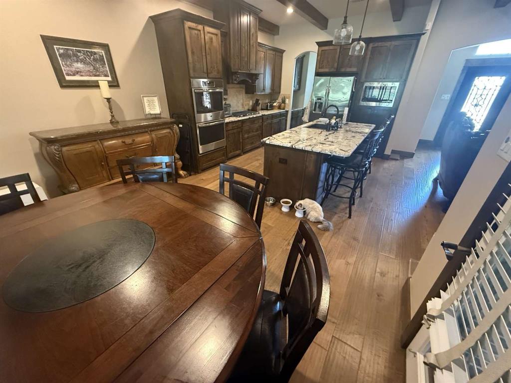 125 Lucky Ridge Lane Boyd, TX 76023 - Photo 16 of 29 Kitchen with a kitchen island with sink, dark brown cabinets, light wood finished floors, stainless steel appliances, and a breakfast bar