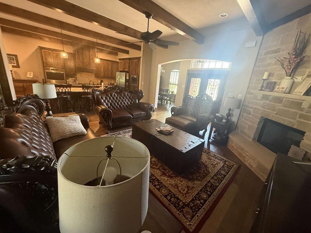 125 Lucky Ridge Lane Boyd, TX 76023 - Photo 18 of 29 Living room featuring dark wood-style flooring, ceiling fan, arched walkways, beam ceiling, and a fireplace