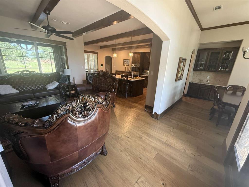 125 Lucky Ridge Lane Boyd, TX 76023 - Photo 20 of 29 Living room with beam ceiling, arched walkways, wood finished floors, ceiling fan, and healthy amount of natural light