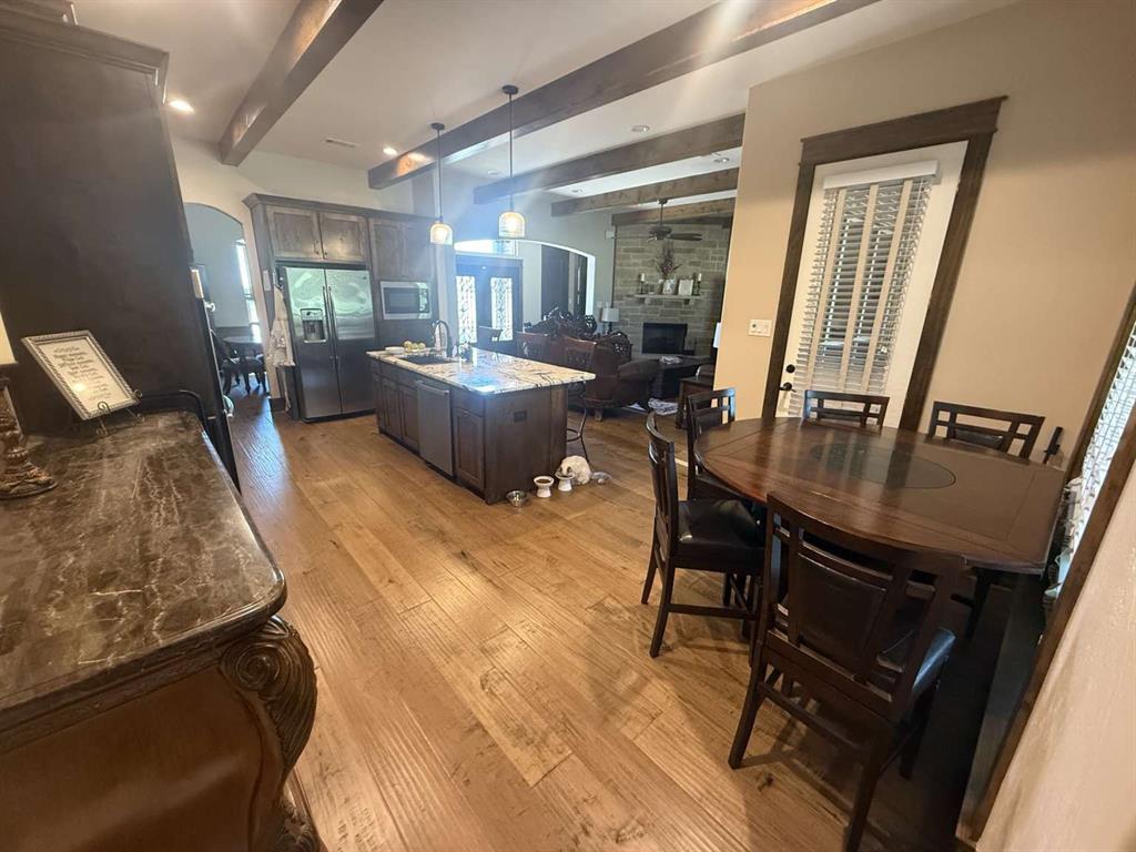 125 Lucky Ridge Lane Boyd, TX 76023 - Photo 21 of 29 Dining space with beamed ceiling, a fireplace, light wood finished floors, arched walkways, and ceiling fan