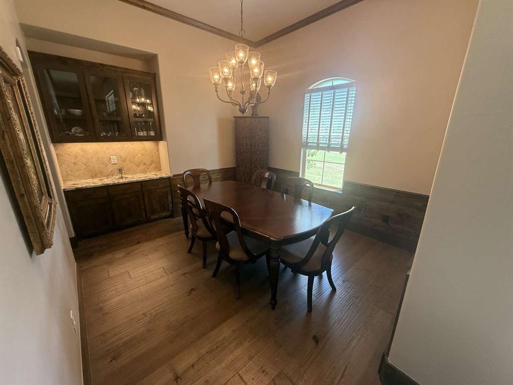 125 Lucky Ridge Lane Boyd, TX 76023 - Photo 23 of 29 Dining space with ornamental molding, wainscoting, wood finished floors, and a chandelier