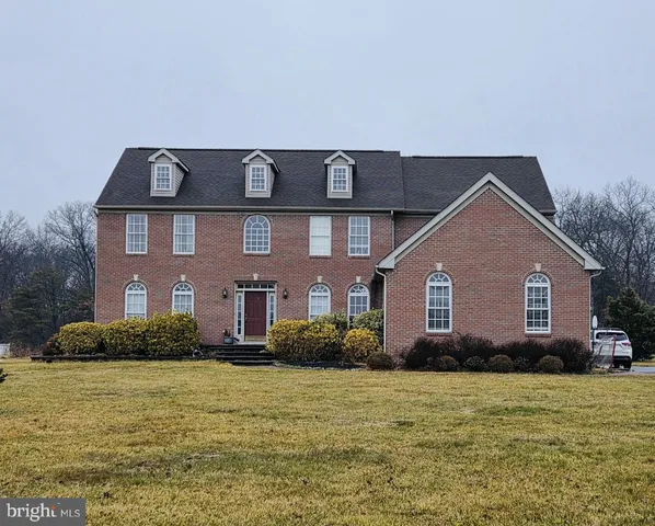 a front view of house with yard and trees in the background